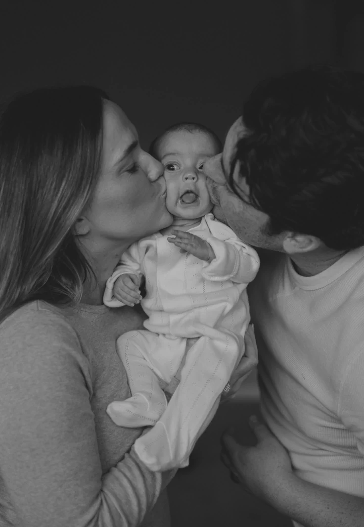 Parents kissing their newborn baby